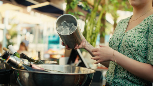 Bartender häller is i en hink på en utomhusbar en solig sommardag i Luleå