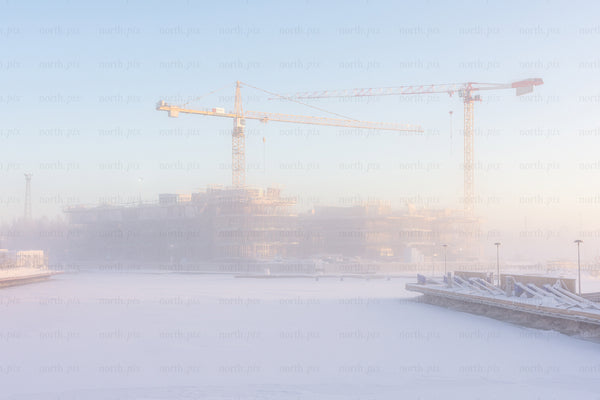 Construction cranes over frozen harbor in winter morning
