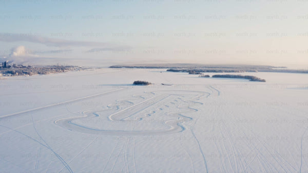 Aerial view of snowy Luleå landscape with snowmobile track on frozen lake in winter morning