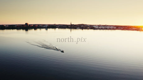 Sunset Over Luleå: A Boat Sails Across the Calm Water of the Swedish City