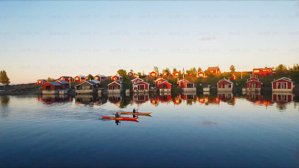 Kayaking in Luleå archipelago at sunset with red cabins: A summer drone view