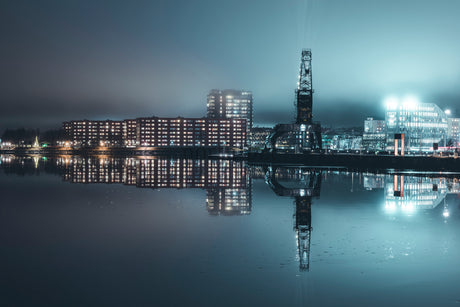 Industrial Crane and Waterfront City Reflection at Night With Foggy Blue Lighting and Urban Buildings