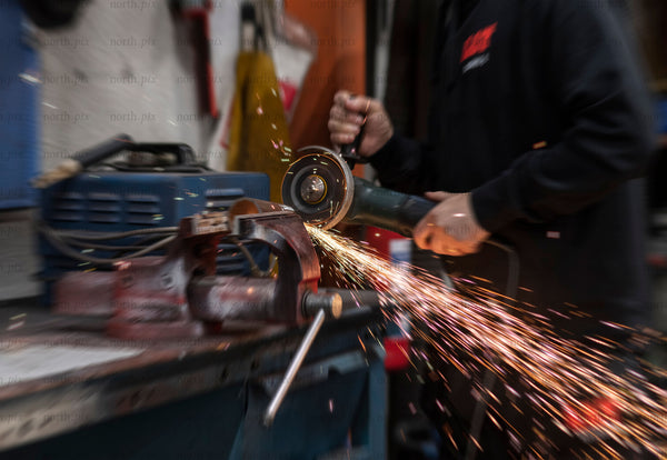 Worker using angle grinder in metal workshop