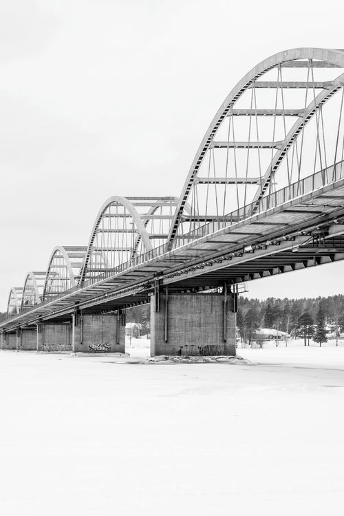 Bågbro över frusen flod i vinterlandskap