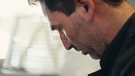 Focused Chef in Black Uniform Prepares Food in a Professional Kitchen