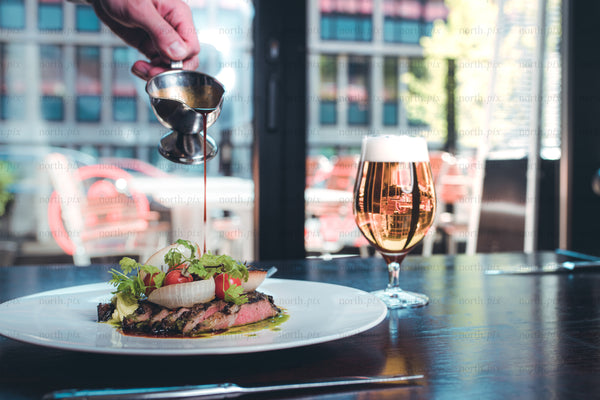 Plated steak with sauce and beer at restaurant, daytime