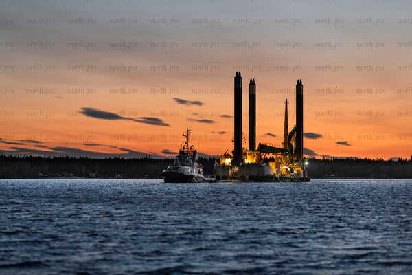 Work barge and tugboat at sunset over water