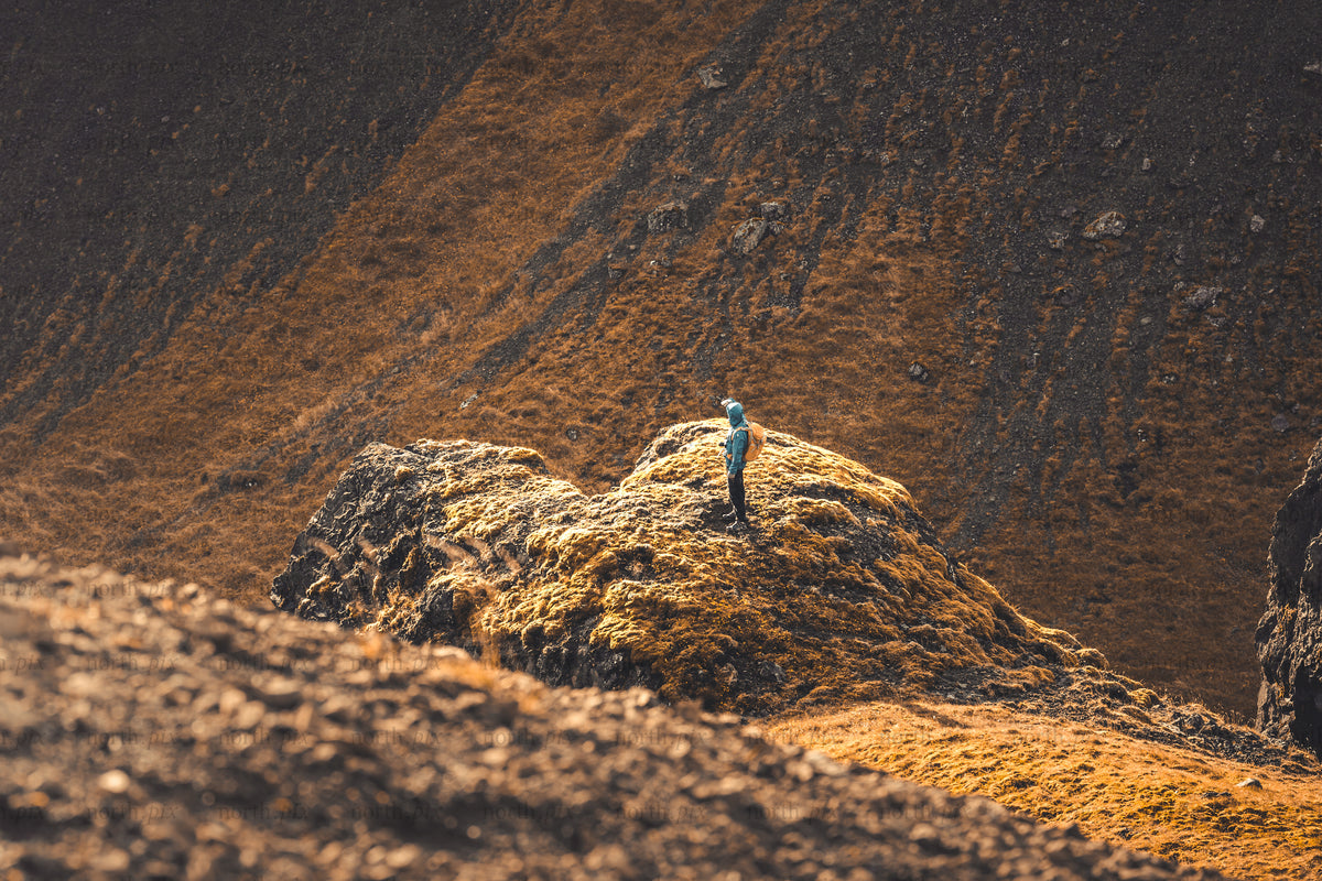 Hiker standing on mossy rock outcrop on hillside