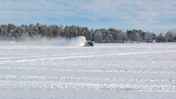 Tractor clearing snow on frozen lake in Luleå winter landscape