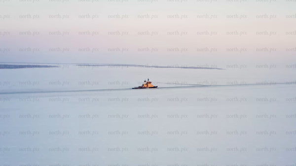 Icebreaker navigating frozen waters of Luleå archipelago at sunset