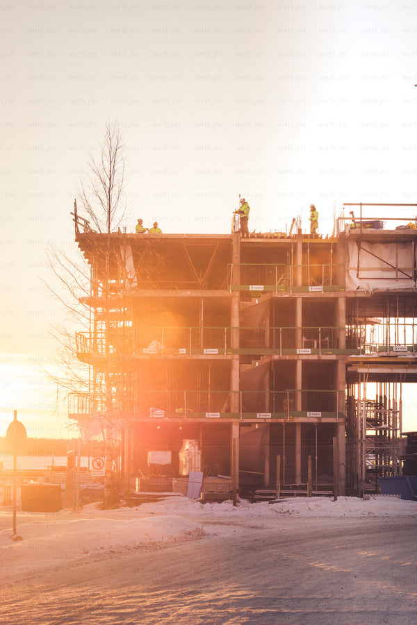 Construction site with workers at sunrise, winter
