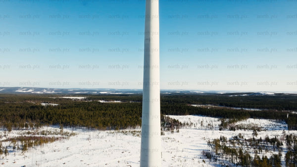 Wind turbine rotating in snowy landscape, Sweden, winter, green energy, aerial upward drone shot
