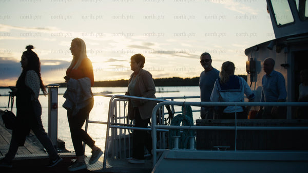 Friends and family disembark boat on pier in Luleå at sunset