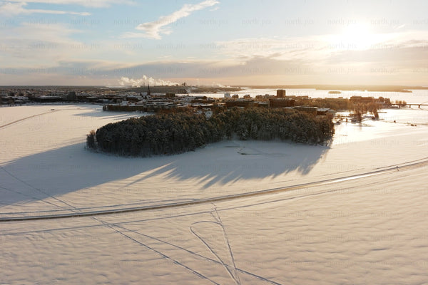 Aerial winter view over Luleå city center with snow covered island and sunset