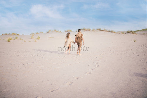 Couple walking on sand dunes at midday