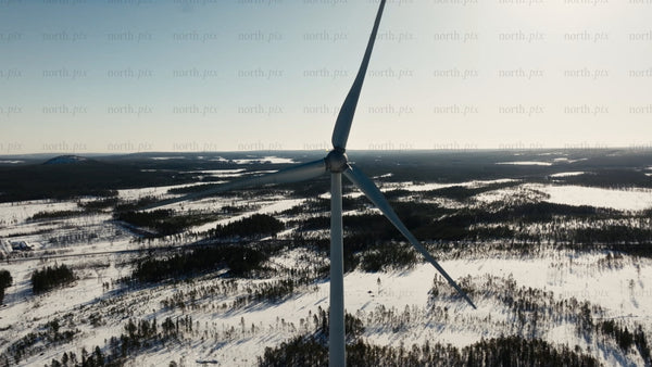 Wind turbine rotating in snowy winter landscape: Aerial view of renewable energy