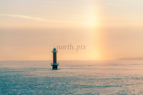 Lighthouse on frozen sea at sunrise