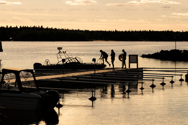 People boarding boat at dock at sunset