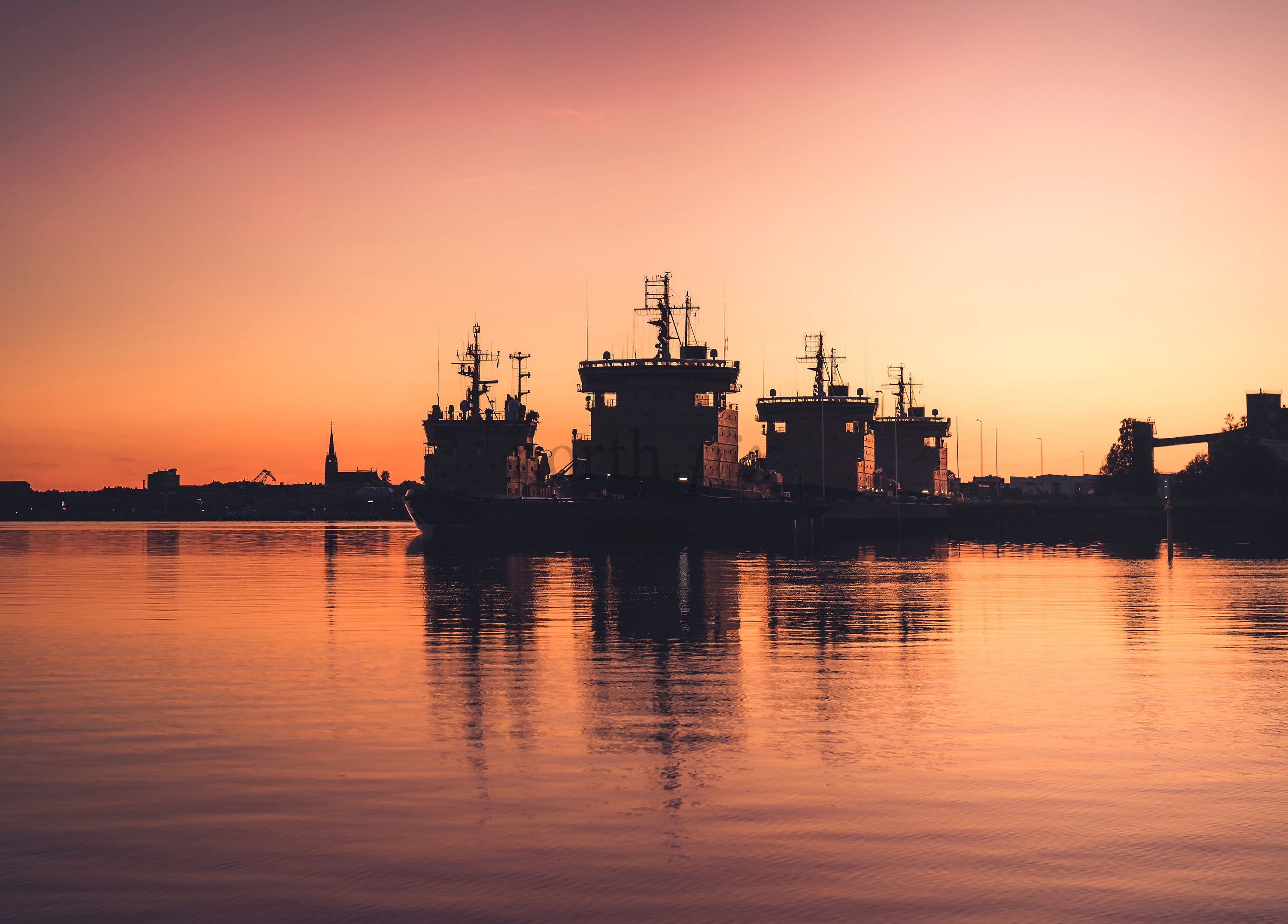 Tugboats and ships at harbor at sunset