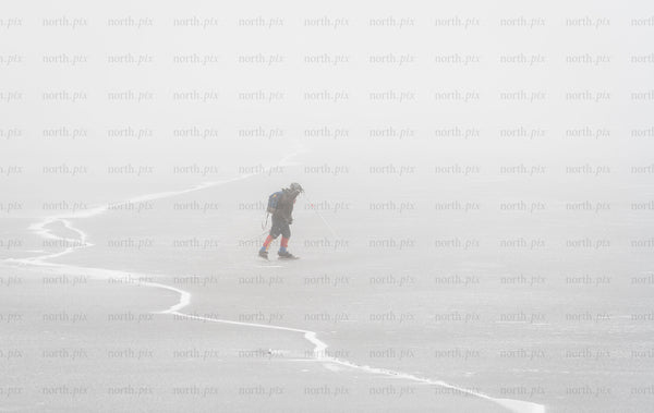 Skier crossing frozen lake in fog on winter day