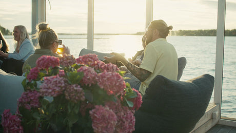 Friends Enjoying Sunset Drinks and Conversation by the Lake in Lulea, Sweden