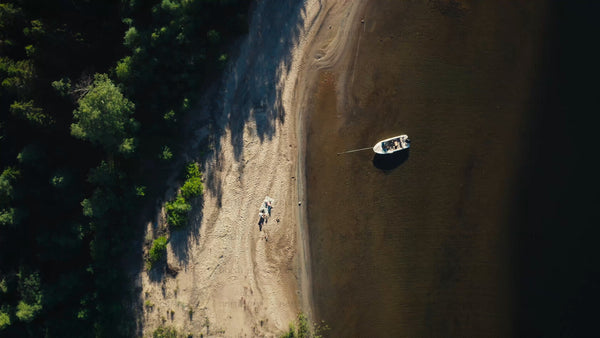 Summer day in Luleå archipelago: Aerial view of beach, boat, and people