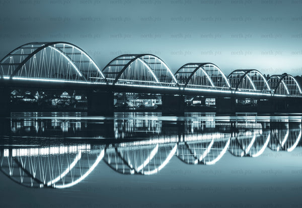Illuminated arched bridge with reflection over river at night