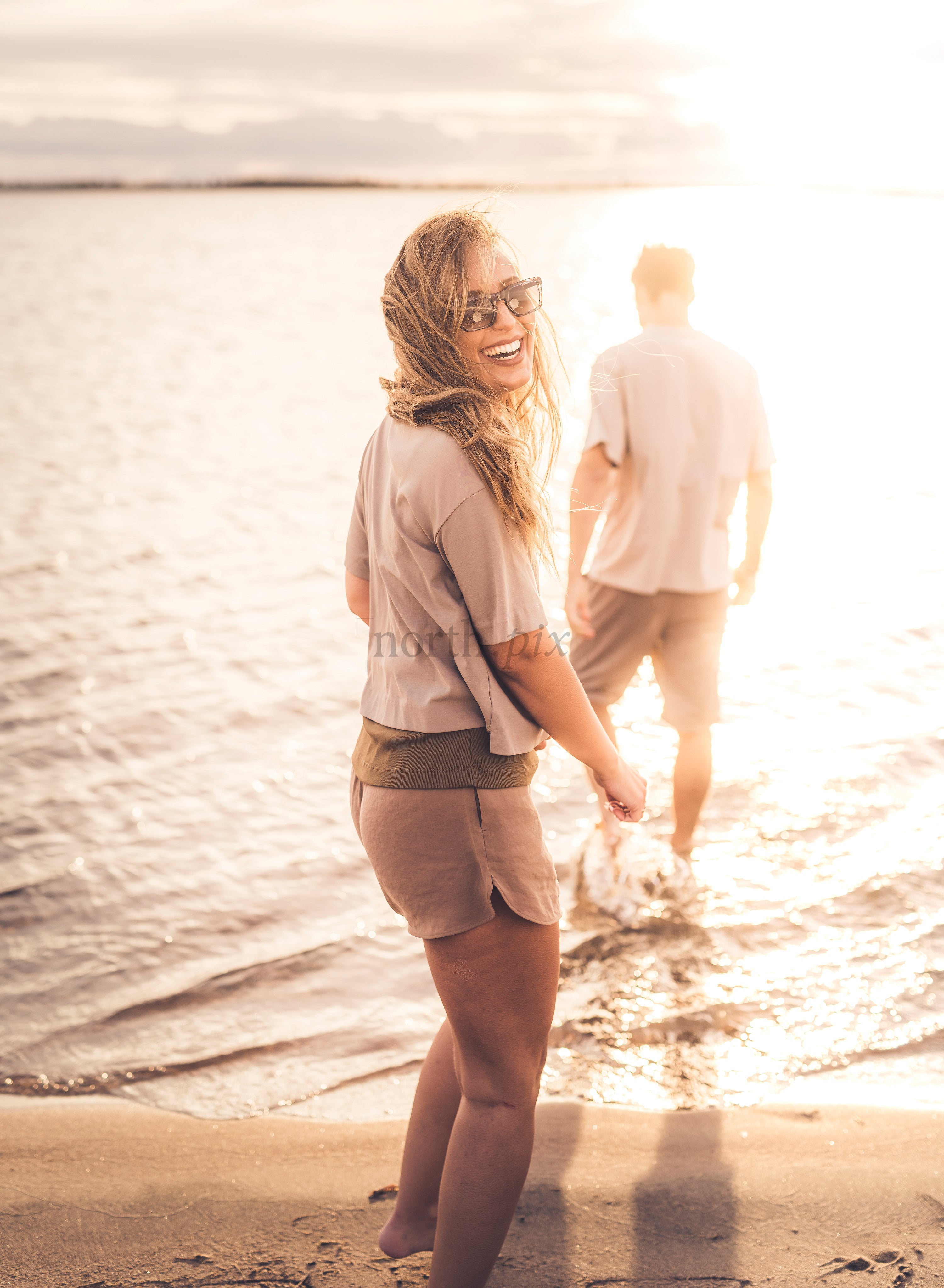Woman smiling on beach at sunset with companion