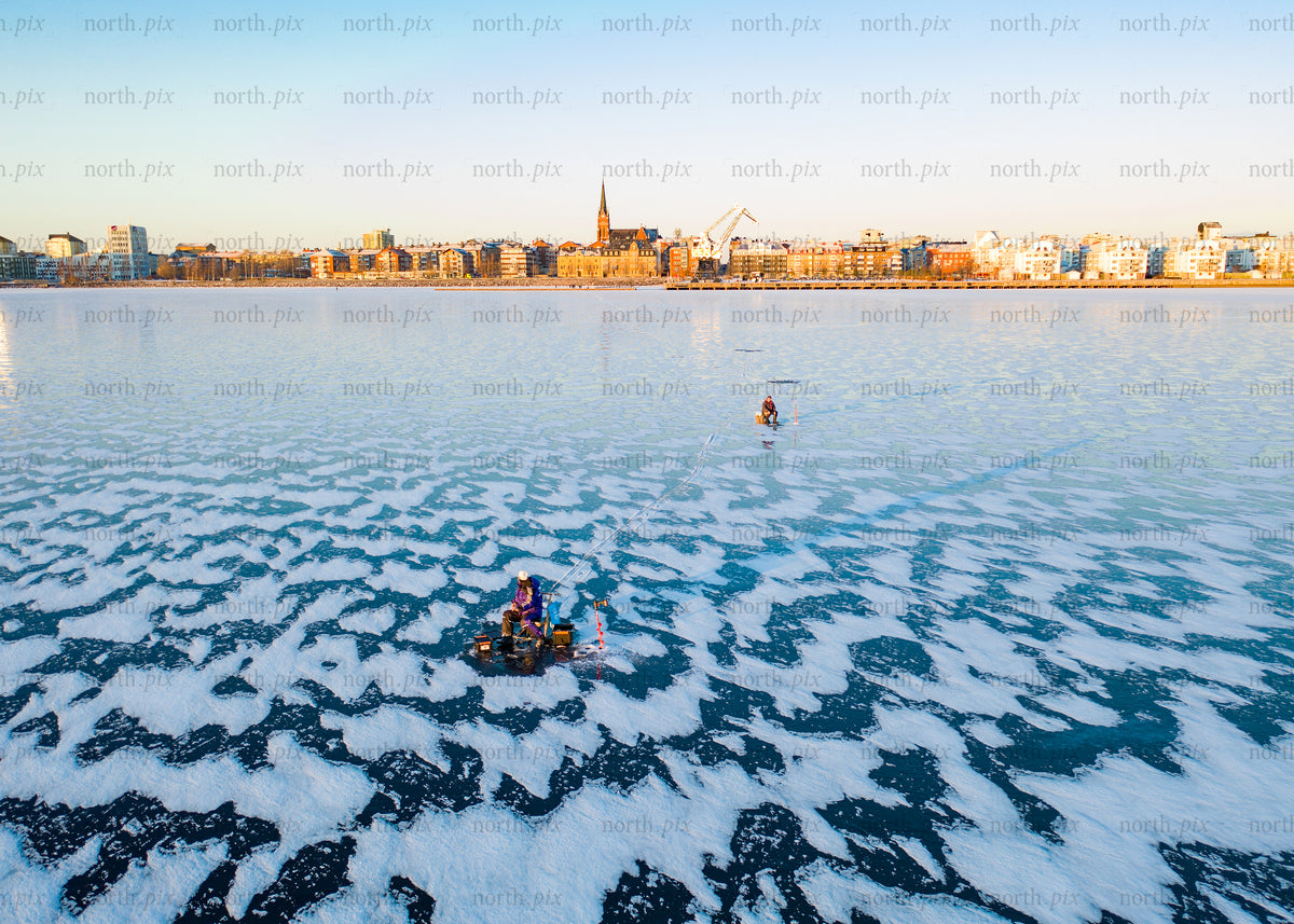 Winter cityscape view of frozen lake with people in morning light