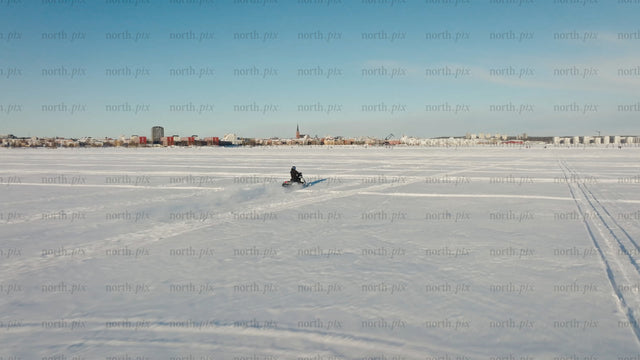 Snowmobile riding across frozen lake in Luleå - winter landscape