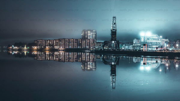 Industrial crane and waterfront buildings at night panorama