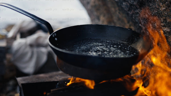 Melting butter in a frying pan over campfire in winter, Luleå