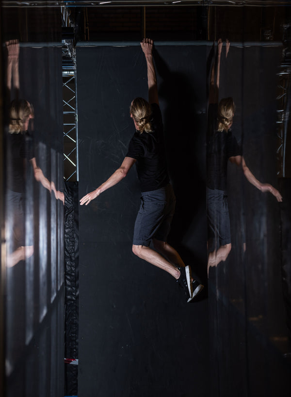 Person hanging from indoor wall with mirrored panels