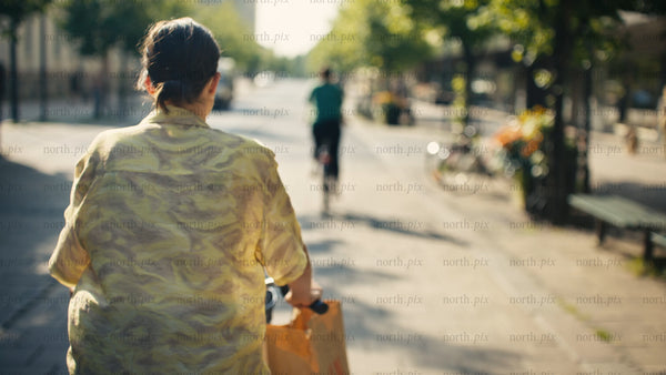Woman on bike in Luleå city on sunny summer day - urban commute