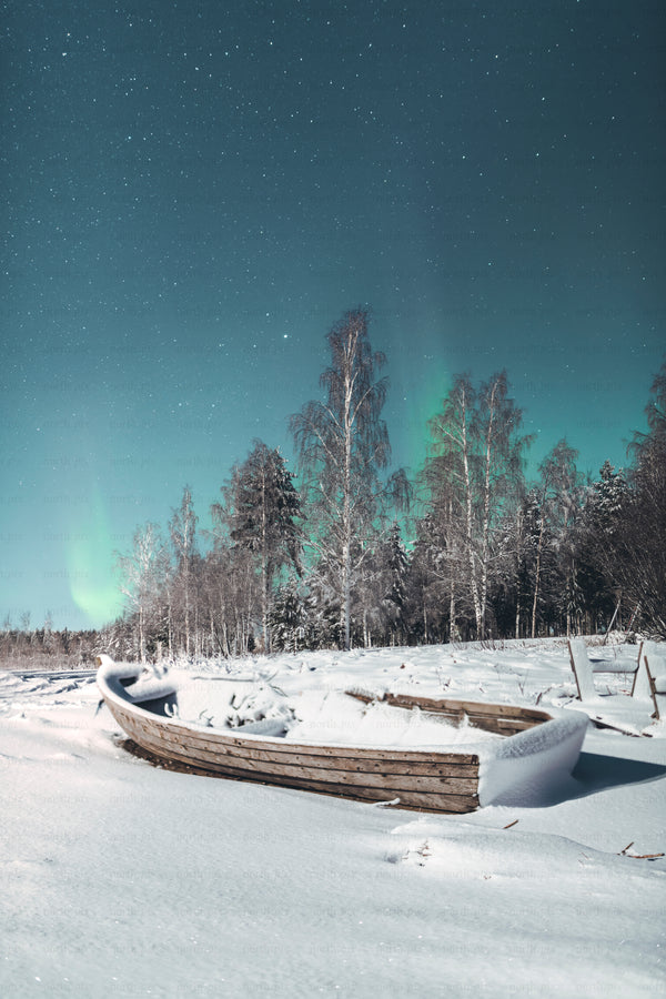 Wooden boat covered in snow under Aurora Borealis
