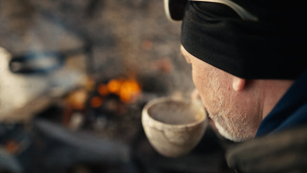 Man enjoys hot drink by campfire in winter, Luleå archipelago