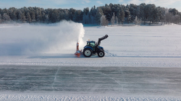 Tractor clearing snow on frozen lake in winter Luleå - aerial drone footage