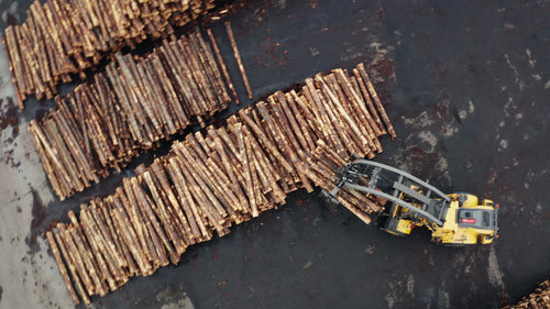 Flygfoto över skogsbruksindustrins anläggning med stockar och gaffeltruck