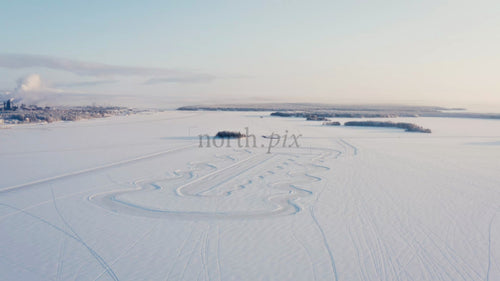 Flygfoto över snötäckt landskap i Luleå med snöskoterspår på frusen sjö på vintermorgon
