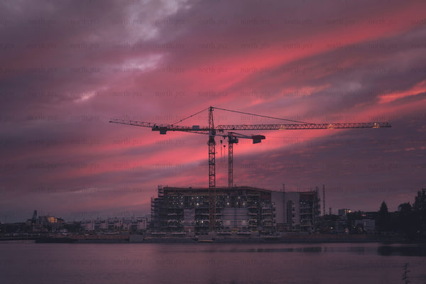 Construction cranes over waterfront building at dusk