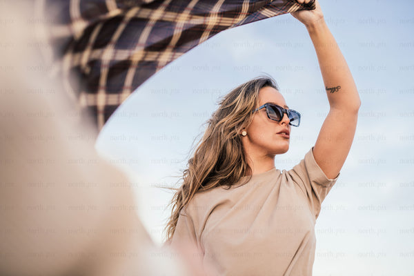 Woman holding a plaid scarf overhead on a windy day