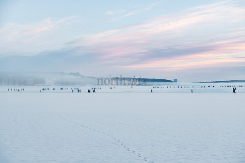 People on frozen sea at sunrise, winter