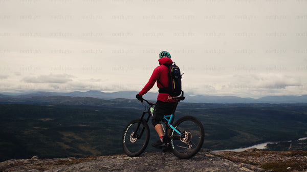 Mountain biker at summit before downhill ride - scenic valley view