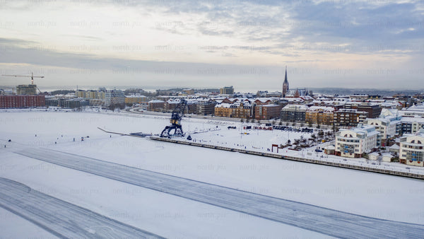 Winter in Luleå: Ice skating on a frozen lake at dusk - aerial view of cityscape