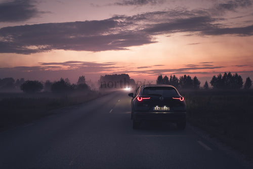 Car parked at roadside at dusk with fog