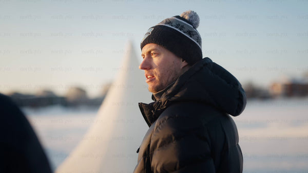 Man in winter clothes by frozen lake in Luleå, on a sunny day