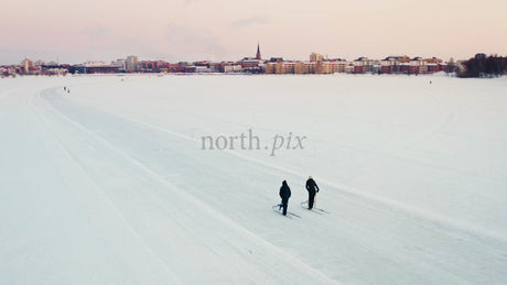 Winter Sunset Cross-Country Skiing on Frozen Lake in Lulea, Sweden with City in Background