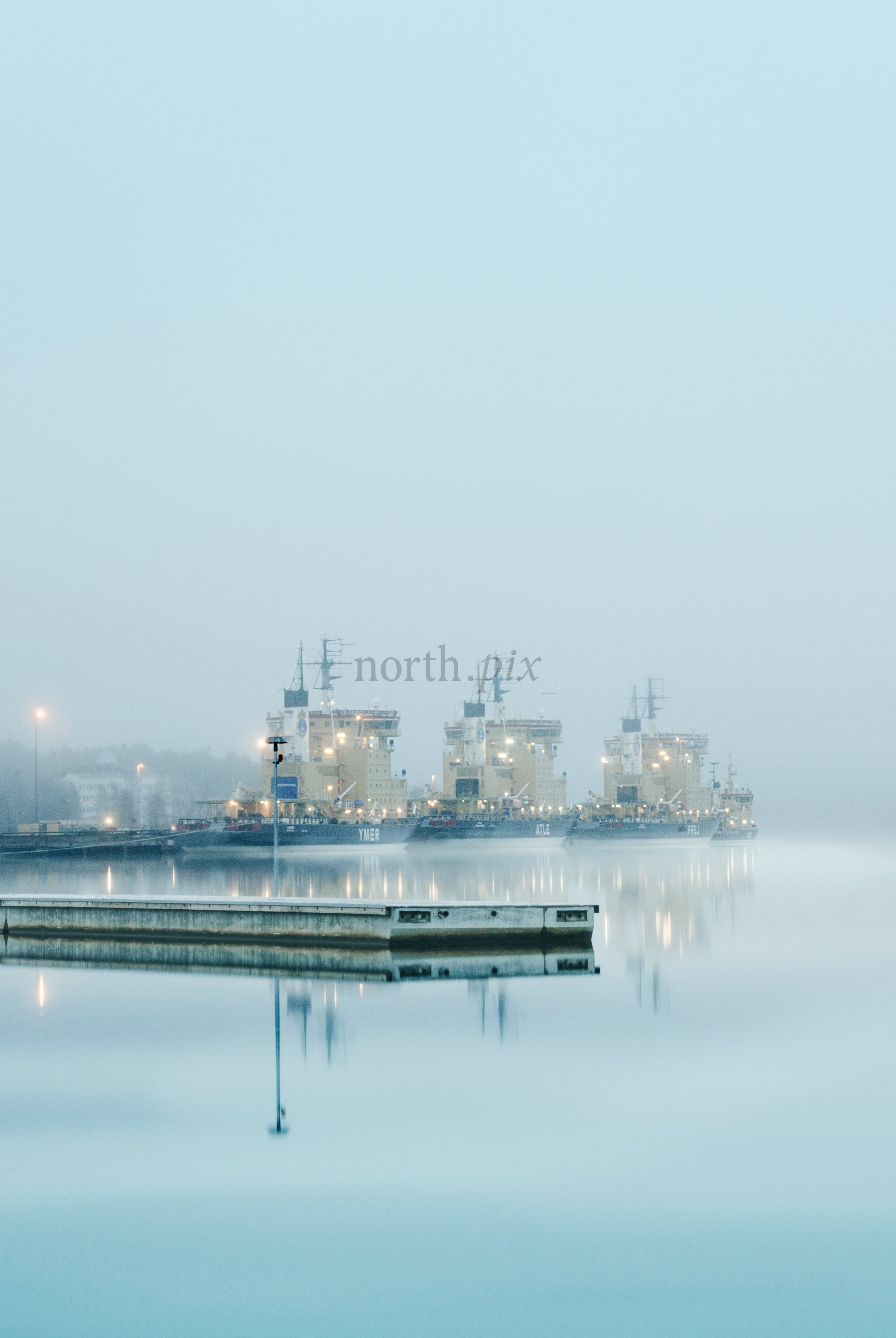 Three icebreakers docked at harbor in fog