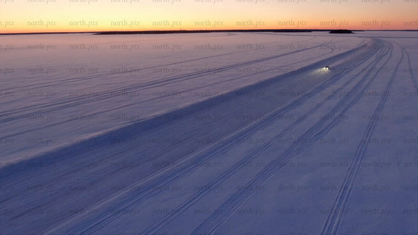 Car driving on ice road at sunset in Luleå archipelago – aerial view