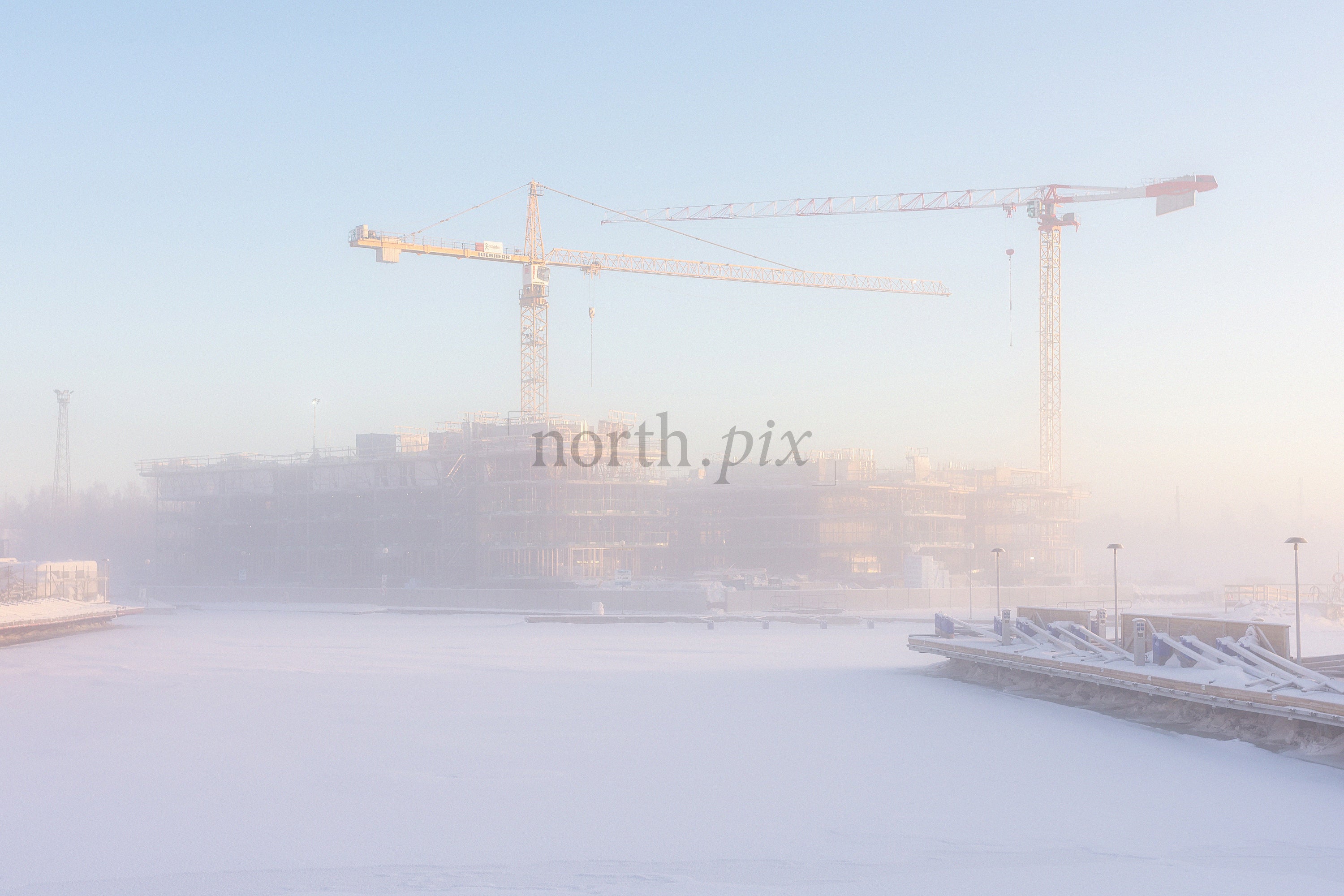Construction cranes over frozen harbor in winter morning